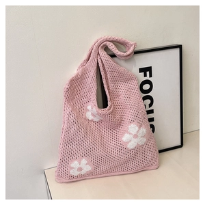 Detail of pink knitted tote bag showing white crochet flower patterns and soft texture