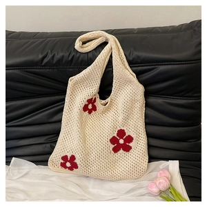 Close-up of retro crochet knit bag with red floral pattern on quilted black background