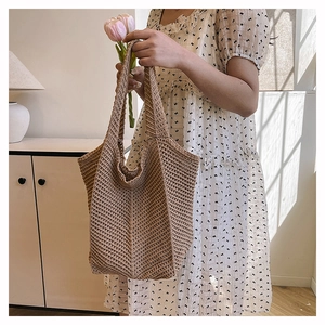 Detail of a brown knit tote bag with thick texture and wide shoulder strap