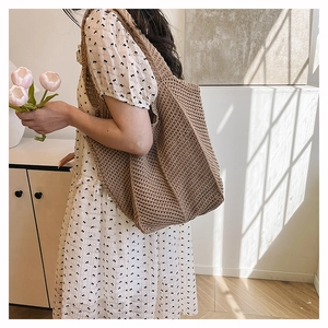 Detailed close-up of brown knit tote bag with thick crochet texture worn by a model