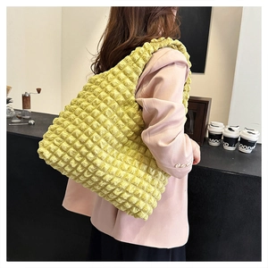 Detail of vibrant yellow puffer tote bag with bubble texture and wide shoulder strap