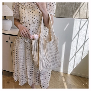 Detail of off-white hand-knitted crochet tote bag with hollow mesh pattern in home setting