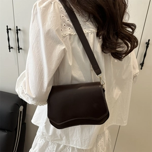 Deep brown minimalist crossbody bag with unique wave-edge flap and gold metal hardware