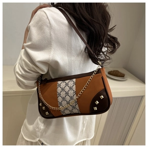 Detail of color-block underarm bag with gold chain strap and floral fabric texture