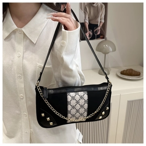 Detail of vintage black leather underarm bag with metal chain and geometric pattern