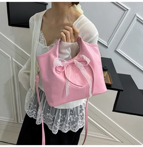 Detalle de bolso de cuero rosa con un lazo de encaje blanco y correa de hombro ajustable