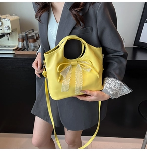 Detalle de bolso amarillo con lazo de cuero y encaje blanco sobre blazer gris