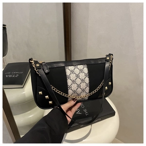 Detail of retro shoulder bag with black and white geometric fabric inlay and gold chains