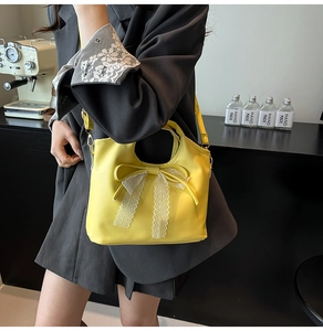 Detalle de bolso de cuero amarillo brillante con lazo de encaje blanco y correa