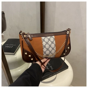Detail of color-block underarm bag with geometric fabric strip and gold studs