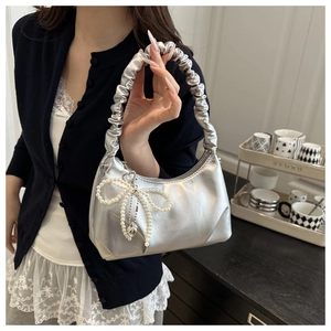 Detail of silver metallic cloud bag with ruched handle and pearl bow heart charm