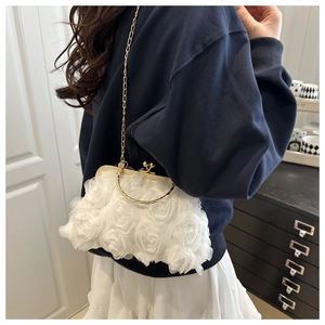 Detail of white 3D floral petals on elegant handbag with gold clasp and chain strap