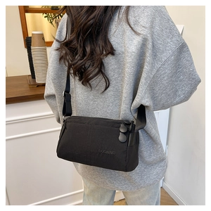 Detailed back view of a black DUONING crossbody bag with adjustable strap on a model
