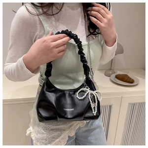 Detail of black cloud pleated handle handbag with pearl bow and gold chain strap