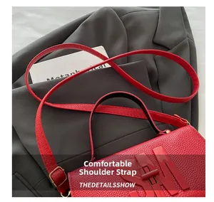 Macro detail of red litchi leather handbag featuring a bold 3D SM logo and adjustable strap