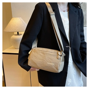 Beige waterproof nylon crossbody bag with adjustable strap worn by model in casual style