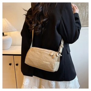 Close-up of khaki nylon crossbody bag with gold lettering and adjustable shoulder strap
