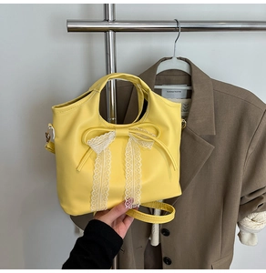 Detalle de bolso de cuero amarillo con encaje blanco y un lazo decorativo a juego