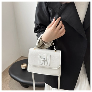 Close-up of white pebble leather handbag with SM metal logo and stylish top handle