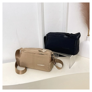 Detail of minimalist nylon crossbody bag with zipper compartments and adjustable strap