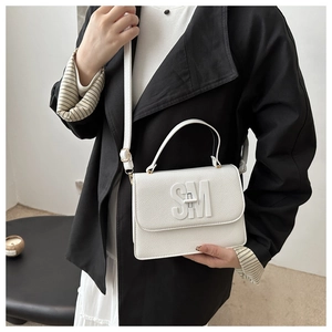 Detail of white lychee leather handbag featuring 3D SM logo and metal turn-lock closure