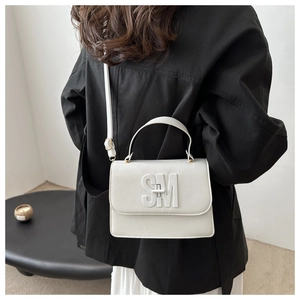 Detail of white lychee leather texture with 3D SM metallic logo and top handle