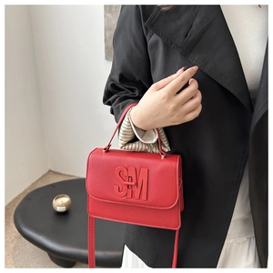 Detail of red pebbled leather handbag featuring 3D SM logo and stylish top handle
