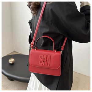 Close-up of red lychee grain leather handbag featuring a 3D SM logo and shoulder strap