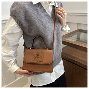 Detail of brown litchi pattern leather square bag with large metal SM logo and thin strap