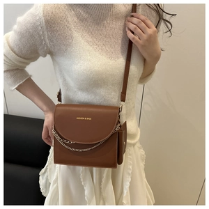 Detail view of brown vintage leather crossbody bag with gold chain and matching mini pouch