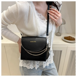 Modische schwarze Leder-Umhängetasche mit goldenen Ketten, von einem Model getragen