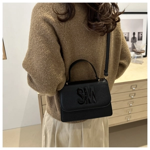 Close-up of black lychee grain handbag featuring a shiny 3D SM logo and slender strap