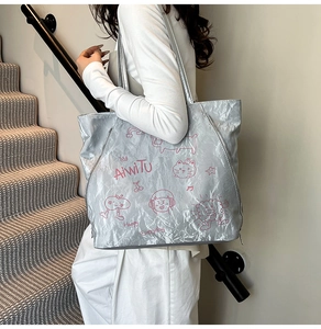 Detail of silver metallic tote bag featuring pink cat graffiti and crinkled texture