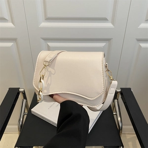 Minimalist beige leather shoulder bag with wavy edge and gold chain strap detail