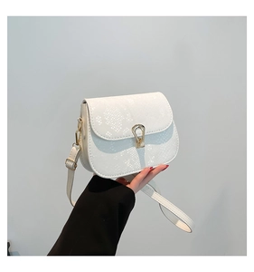 Détail du sac selle blanc effet serpent avec boucle dorée en U et texture raffinée