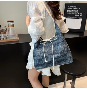 Detail of blue denim tote bag featuring a white drawstring bow and decorative beads