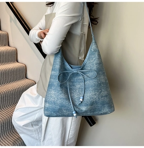 Detail of denim tote bag showing bow drawstring closure and blue bead accents