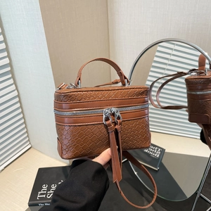 Braune gewebte Box-Handtasche mit silbernen Reißverschlüssen und Griff im Spiegel gezeigt