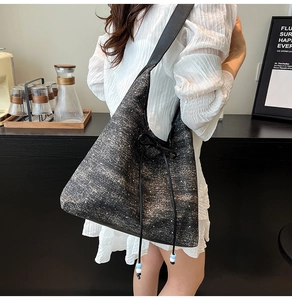 Dettaglio della borsa shopper nera glitterata con fiocco e tracolla decorata con perle