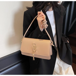 Detail of apricot matte leather crossbody bag with gold hardware and tassel on model