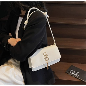 Detail of white leather shoulder bag with golden S-buckle and elegant tassel accessory
