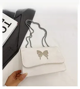 Detail of white chain shoulder bag featuring a silver metal butterfly buckle and leather texture