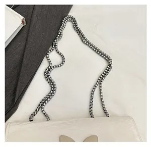 Detail of white wrinkled leather bag with silver ball chain and butterfly shaped buckle
