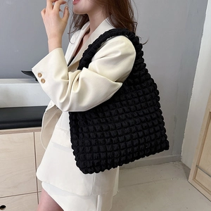 Large black puffer tote bag with pleated bubble texture shown on a female model