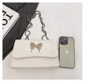White leather chain bag featuring a silver butterfly buckle shown with a smartphone