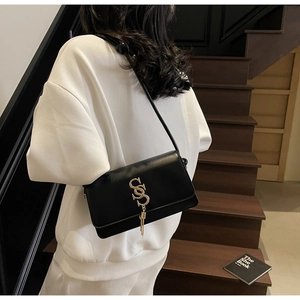 Chic black leather flap bag with gold SS logo and tassel detail shown on shoulder