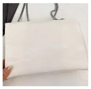 Detailed close-up of white flap shoulder bag with wrinkled texture and silver chain strap