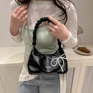 Black ruched cloud bag with silver chain and pearl bow charm shown in lifestyle setting