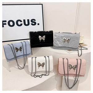Detail view of stylish crossbody bags with butterfly clasps and pleated texture in five colors