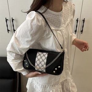Vintage black underarm bag with contrast clover pattern and gold chain detail on model